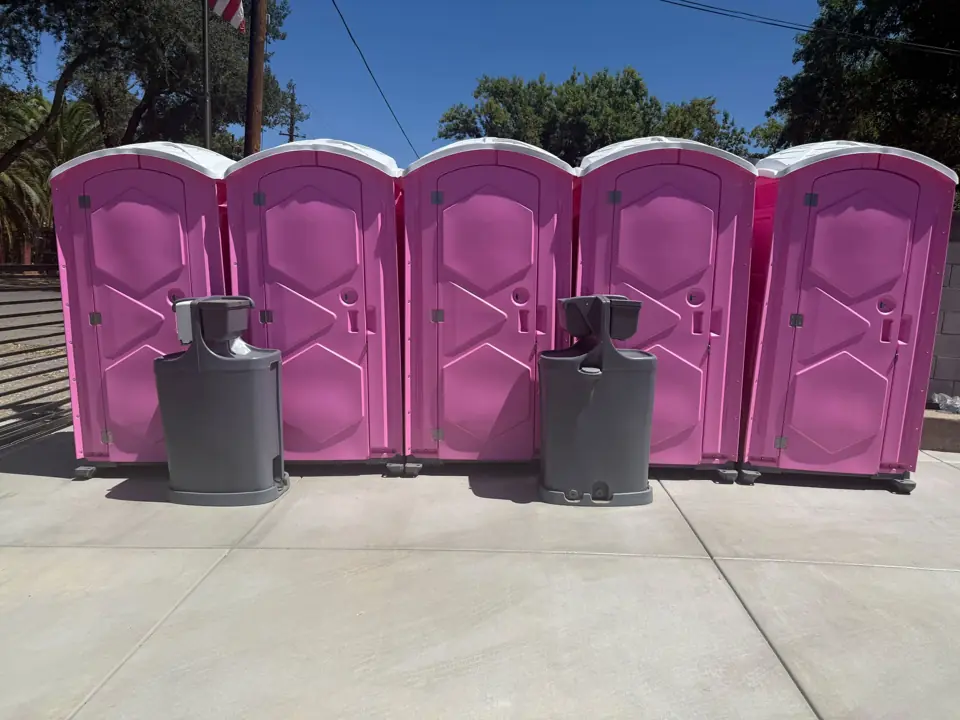 Row of pink porta potties with freestanding handwash stations