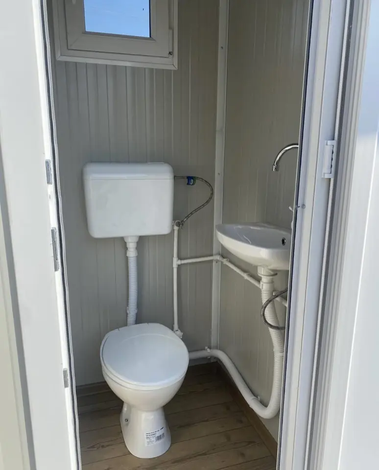 VIP restroom cabin interior with flush toilet, cistern and corner sink
